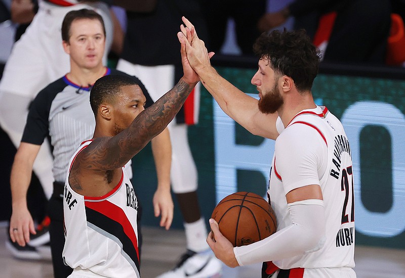 Portland Trail Blazers' Damian Lillard, left, and Jusuf Nurkic celebrate the team's win over the Philadelphia 76ers in an NBA basketball game Sunday, Aug. 9, 2020, in Lake Buena Vista, Fla. (Kevin C. Cox/Pool Photo via AP)