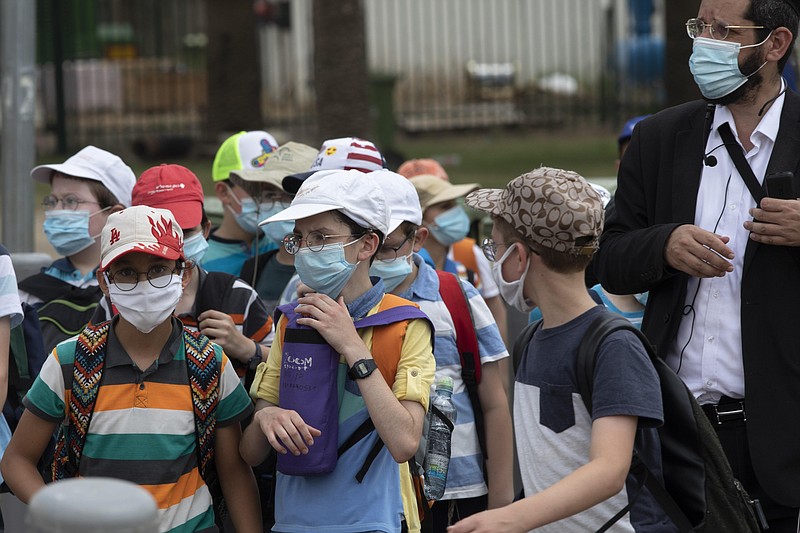 File---File picture taken July 6, 2020 shows Israeli school children wearing face masks to help prevent the spread of the coronavirus as they walk in Tel Aviv, Israel. As Germany’s 16 states start sending millions of children back to school in the middle of the global coronavirus pandemic, those used to the country’s famous “Ordnung” are instead looking at uncertainty, with a hodgepodge of regional regulations that officials acknowledge may or may not work. (AP Photo/Sebastian Scheiner,File)