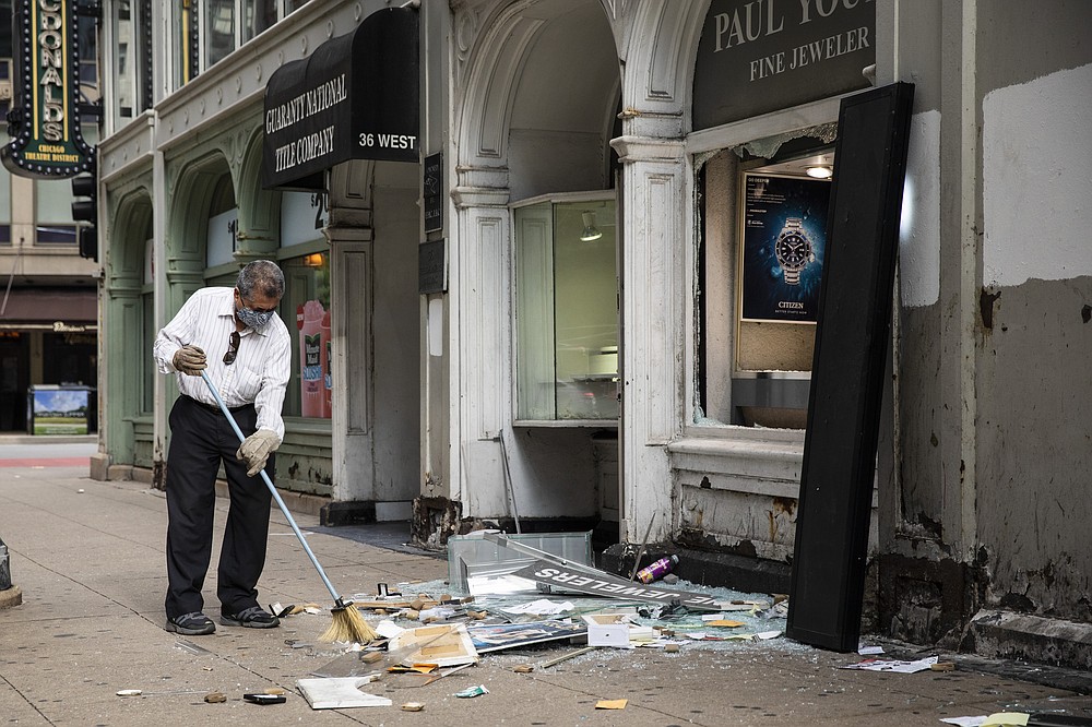 A man sweeps up outside Paul Young Fine Jewelers after looting broke out in the Loop and surrounding neighborhoods overnight, Monday morning, Aug. 10, 2020 in Chicago. Police Superintendent David Brown says when police shot a man who opened fire on officers Sunday, the incident apparently prompted a social media post urging looters to converge on the business district.  (Ashlee Rezin Garcia /Chicago Sun-Times via AP)