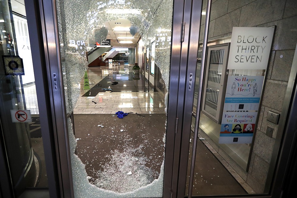 A door to the Block 37 retail building is shattered Monday, Aug. 10, 2020, after vandals struck overnight in Chicago's famed Loop. Chicago’s police commissioner says more than 100 people were arrested following a night of looting and unrest that left several officers injured and caused damage in the city’s upscale Magnificent Mile shopping district and other parts of the city. (AP Photo/Charles Rex Arbogast)