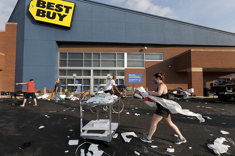 Volunteers help clean up the parking lot outside a Best Buy store, Monday, Aug. 10, 2020, after vandals struck overnight in the Lincoln Park neighborhood in Chicago. Chicago’s police commissioner says more than 100 people were arrested following a night of looting and unrest that left several officers injured and caused damage in the city’s upscale Magnificent Mile shopping district and other parts of the city. (AP Photo/Charles Rex Arbogast)