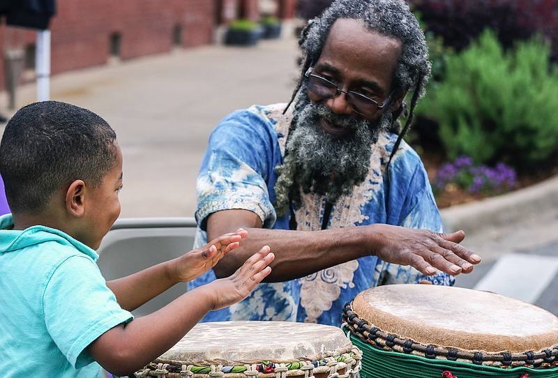 Masen Gober, 3, of Benton, has some fun on the djembe, a traditional African drum, with Searcy Ewell of Little Rock during the Africa Day Fest at Bernice Gardens in Little Rock Saturday, May 27, 2017. (Arkansas Democrat-Gazette/MITCHELL PE MASILUN)