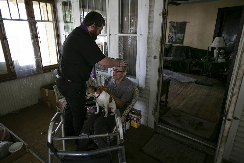 Father Kristopher Cowles of Our Lady of Guadalupe Church offers a blessing to Doug Van Loh, 62, at his home as Sadie stands by. Van Loh is a longtime member of the church who is now housebound. Father Cowles visits him regularly.
(Los Angeles Times/TNS/Robert Gauthier)