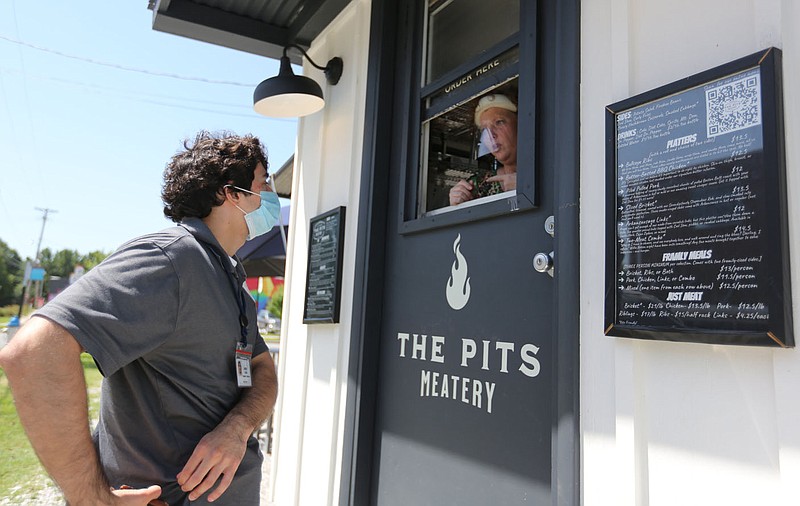 Justin Davis places his lunch order Monday, August 10, 2020, with Jamie Wilkerson, owner of The Pits Meatery, at the food truck style restaurant in downtown Springdale. The Springdale City Council could decide on a downtown entertaiment district that would allow alcohol to be carried from restaurants and even into participating stores. Check out nwaonline.com/200813Daily/ and nwadg.com/photos for a photo gallery.
(NWA Democrat-Gazette/David Gottschalk)