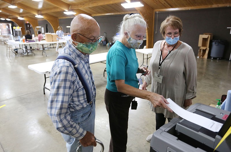 Pat Marcy (from right), Washington County election official, assists Roberta and Richard Harris as they cast their ballots Tuesday, August 11, 2020, at the Rodeo Community Center in Springdale. Voters in Springdale and Bethel Heights went to the polls to decide whether to annex Bethel Heights into Springdale. Residents proposed the annexation to resolve the issue of Bethel Heights' failing sewer system. Check out nwaonline.com/200812Daily/ and nwadg.com/photos for a photo gallery.
(NWA Democrat-Gazette/David Gottschalk)