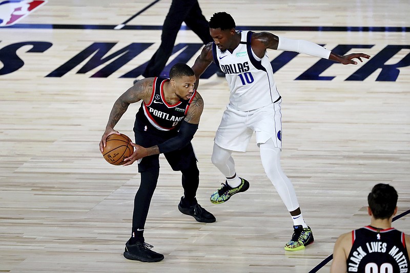 Portland Trail Blazers guard Damian Lillard holds the ball while defended by Dallas Mavericks forward Dorian Finney-Smith (10) during the second half of Tuesday's NBA game in Lake Buena Vista, Fla. - Photo by Kim Klement/Pool Photo via The Associated Press
