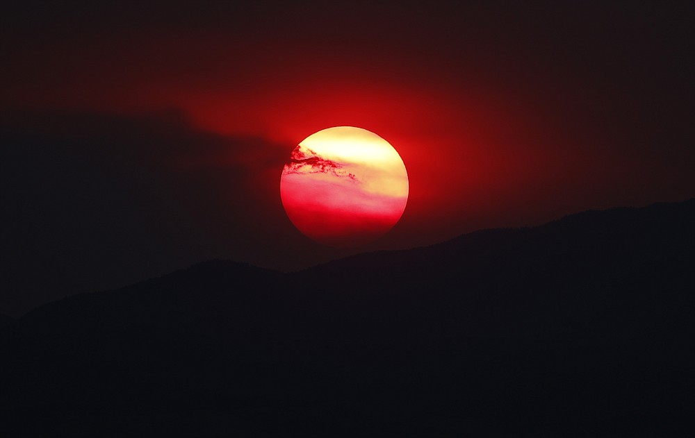 As wildfires burn throughout the Western Slope, the sun sets a bright orange behind the Rocky Mountains for residents of the eastern plains Wednesday, Aug. 12, 2020, in Denver. Forecasters predict the warm weather will persist, vexing firefighters as they deal with the wildland blazes. (AP Photo/David Zalubowski)