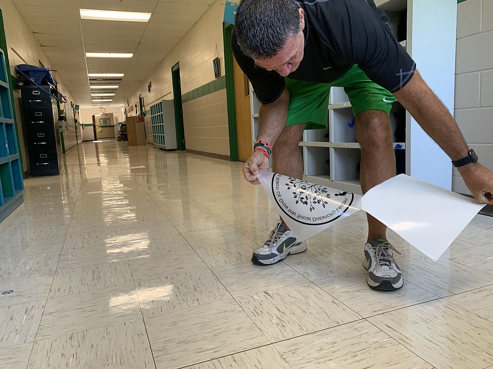 Alan Barton, longtime Greenland Elementary School principal, applies decals to the floor to help students with social distancing Thursday, Aug. 6, 2020, as he and his staff prepare the school to meet social-distancing and other covid-19 standards ahead of the first day of school. Visit nwaonline.com/200807Daily/ for today's photo gallery.
(NWA Democrat-Gazette/Andy Shupe)