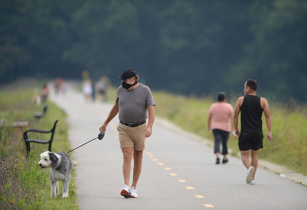 Storm Carr of Fayetteville walks Saturday, Aug. 8, 2020, with his dog, Winnie Mae, along the Lake Fayetteville dam in Fayetteville. The Walton Family Foundation released its 2019 trail usage report, the third one since 2019, which finds that the trail systems in Northwest Arkansas are experiencing a steady rise in bike and foot traffic. Visit nwaonline.com/200809Daily/ for today's photo gallery. (NWA Democrat-Gazette/Andy Shupe)