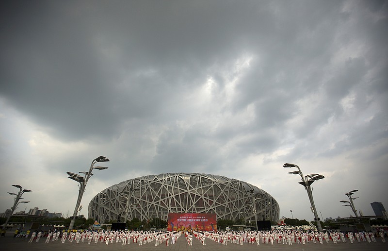 Participants dance under threatening skies at a gathering to watch the announcement of the 2022 Winter Olympics host city outside the Beijing Olympic Stadium, also known as the Birds Nest, in Beijing on July 31, 2015.  The Olympics are remembered for the stars. That was true in Beijing in 2008, and the stars were Michael Phelps and Usain Bolt. But Beijing is also storied for its signature venues like the “Bird's Nest” stadium, and the “Water Cube” swimming venue. No Olympics before — or since — have impacted a city the way the Olympics did Beijing. - Photo by Mark Schiefelbein of The Associated Press