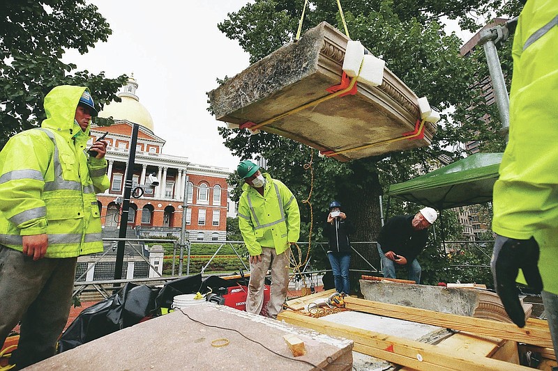 Workers inspect the top cornice stone as it is lifted from the Shaw 54th Regiment memorial opposite the Statehouse, Friday, July 17, 2020, in Boston. Amid the national reckoning on racism, the memorial to the first Black regiment of the Union Army, the Civil War unit popularized in the movie "Glory,” is facing scrutiny. (AP Photo/Michael Dwyer)