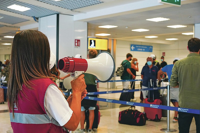 Passengers arriving in Rome from four Mediterranean countries receive instructions by airport staff, right, as they line up with their suitcases at Rome's Leonardo da Vinci airport to be immediately tested for COVID-19, Sunday, Aug.16, 2020. Italy's health minister issued an ordinance requiring the tests for all travelers arriving in Italy from Croatia, Greece, Malta or Spain. (AP Photo/Andrew Medichini)