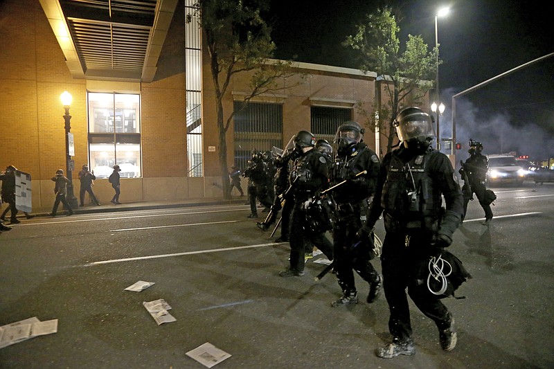 Portland police declare a riot at the Multnomah County Building, on Tuesday, Aug. 18, 2020, in Portland, Ore. Protesters in Portland broke out the windows of a county government building, sprayed lighter fluid inside and set a fire in a demonstration that started Tuesday night and ended Wednesday morning with clashes with police, officials said. (Beth Nakamura/The Oregonian via AP)