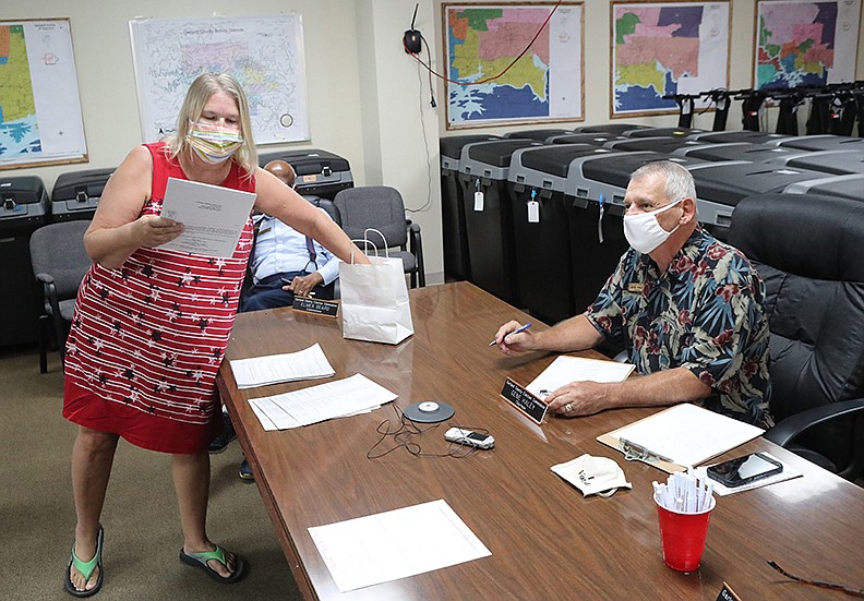 Kathy Edds, left, draws a ballot position for one of the 13 presidential candidates on the ballot for this year’s general election Friday as Garland County Election Commission Chairman Gene Haley looks on. - Photo by Richard Rasmussen of The Sentinel-Record