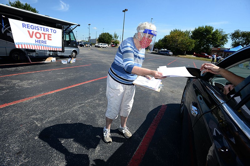 Connie Hoffman (center), a member of the League of Women Voters of Arkansas, helps Kevin Sivley of Garfield and his neighbor Richard Lee to arrange for Lee's absentee ballot Friday, Aug. 21, 2020, while registering people to vote in front of the Walmart Supercenter at 2110 W. Walnut St. in Rogers. Voters must be registered by Oct. 5 to be eligible to vote in the Nov. 3 general election. Visit nwaonline.com/200822Daily/ for the Aug. 21, 2020, photo gallery. (NWA Democrat-Gazette/Andy Shupe)