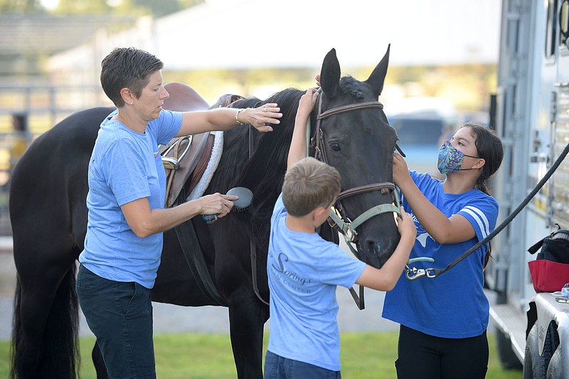 Livia Santschi (from left) of Tontitown, her son, Dean Santschi, 8, and friend Allie O'Connell, 13, of Fayetteville work together Saturday, Aug. 22, 2020, to prepare Raven for the annual Washington County Horse Show at the Pauline Whitaker Animal Science Center in Fayetteville. The fair continues today with the hog and dairy goat shows and runs through Saturday, concluding with the youth dog show. Visit nwaonline.com/200824Daily/ for today's photo gallery.
(NWA Democrat-Gazette/Andy Shupe)