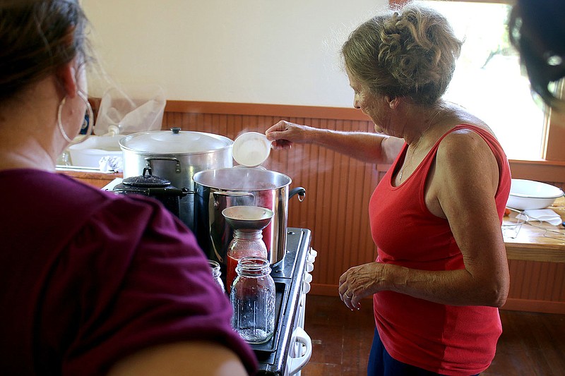 MEGAN DAVIS/MCDONALD COUNTY PRESS RoseAnn Huff (left) watches closely as Karen Almeter skillfully fills canning jars with tomatoes fresh from the New Bethel School's Victory Garden during a class on hot water canning.