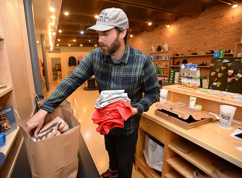 Brian Bailey, owner of The Mustache Goods and Wears on the Fayetteville square, fills orders placed online for curbside pickup April 23 in the store. Retail and online sales have gone up during the pandemic, while restaurants, hotels and department stores have struggled, according to an economic update for the City Council. (File photo/NWA Democrat-Gazette/Andy Shupe)