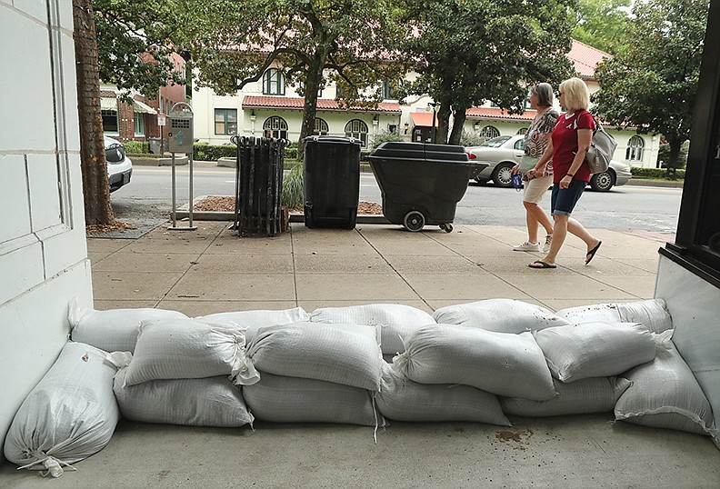 Pedestrians stroll past the sandbagged entrance to The Avenue restaurant in The Waters Hotel in the 300 block of Central Avenue. - Photo by Richard Rasmussen of The Sentinel-Record