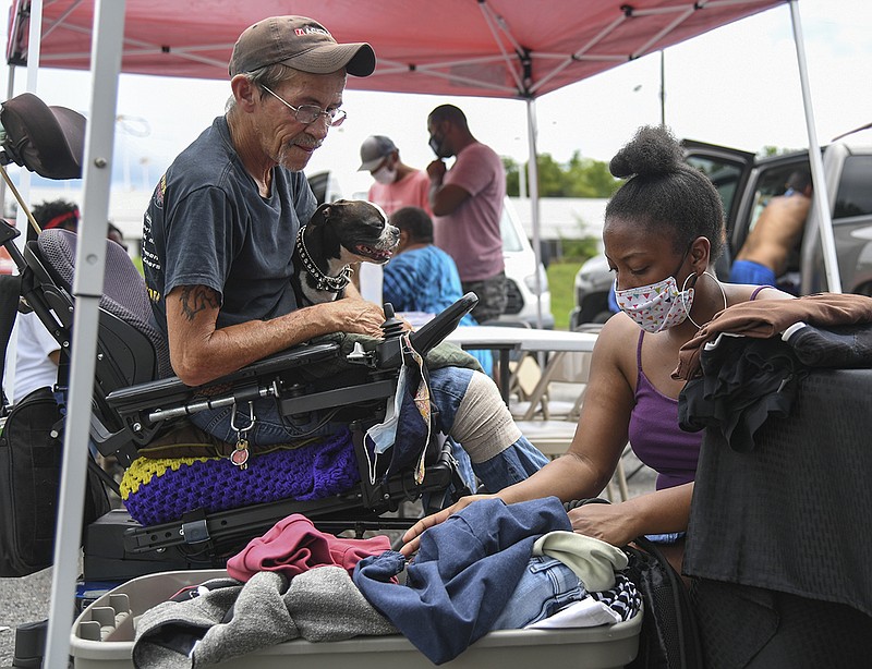 I'Nita White with The Giving team helps Joe Taylor find clothing items he needs from a box during the first Food for Thought on July 25. - Photo by Grace Brown of The Sentinel-Record