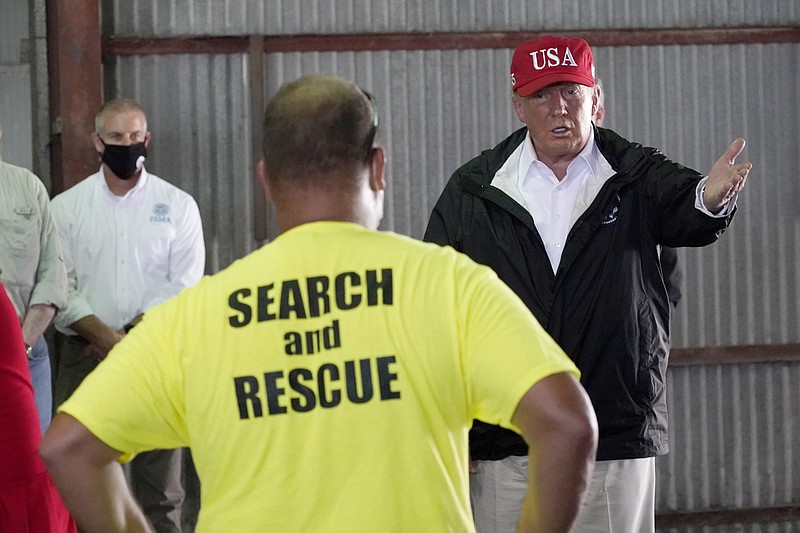 President Donald Trump speaks with first responders as he tours a warehouse being used as a distribution point for relief aid after Hurricane Laura hit the area, Saturday, Aug. 29, 2020, in Lake Charles, La. (AP Photo/Alex Brandon)