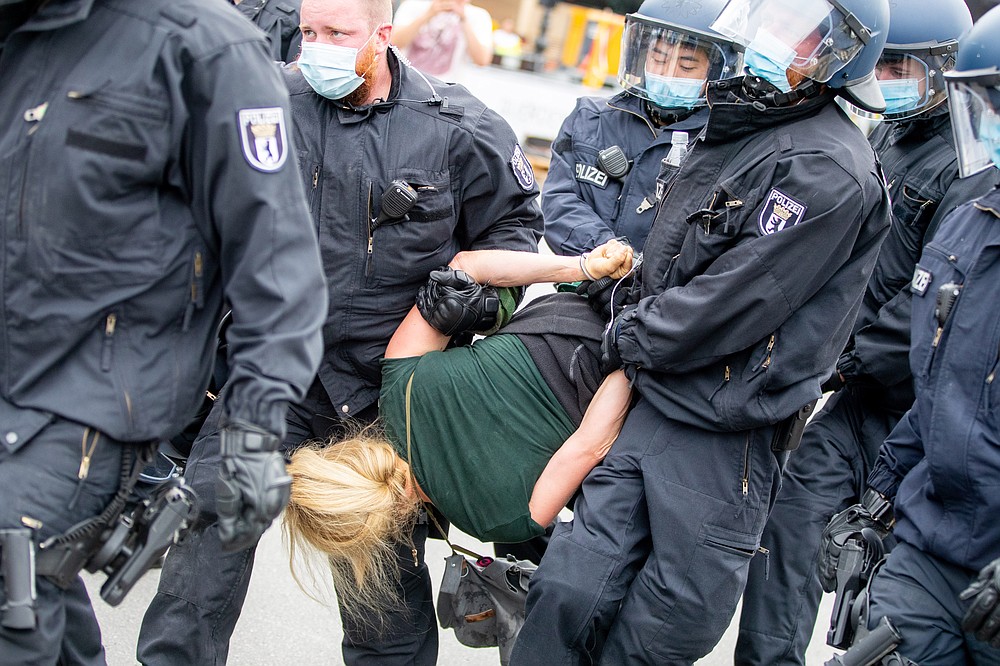 Police officers carry a woman at the Victory Column in a protest against the Corona measures in Berlin, Germany, Sunday, Aug. 30, 2020. (Christoph Soeder/dpa via AP)