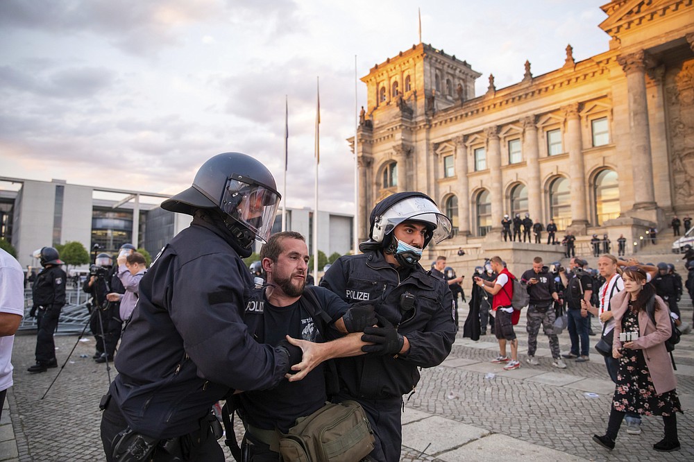 Police officers push away a crowd of demonstrators from the square 'Platz der Republik' in front of the Reichstag building during a demonstration against the Corona measures in Berlin, Germany, Saturday, Aug. 29, 2020. (Christoph Soeder/dpa via AP)