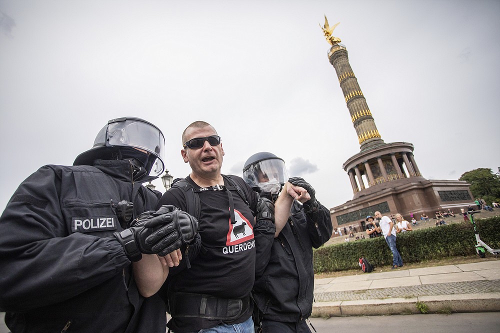 A man is led away by police officers in front of the Victory Column in a protest against the Corona measures in Berlin, Germany, Sunday, Aug. 30, 2020. (Christoph Soeder/dpa via AP)