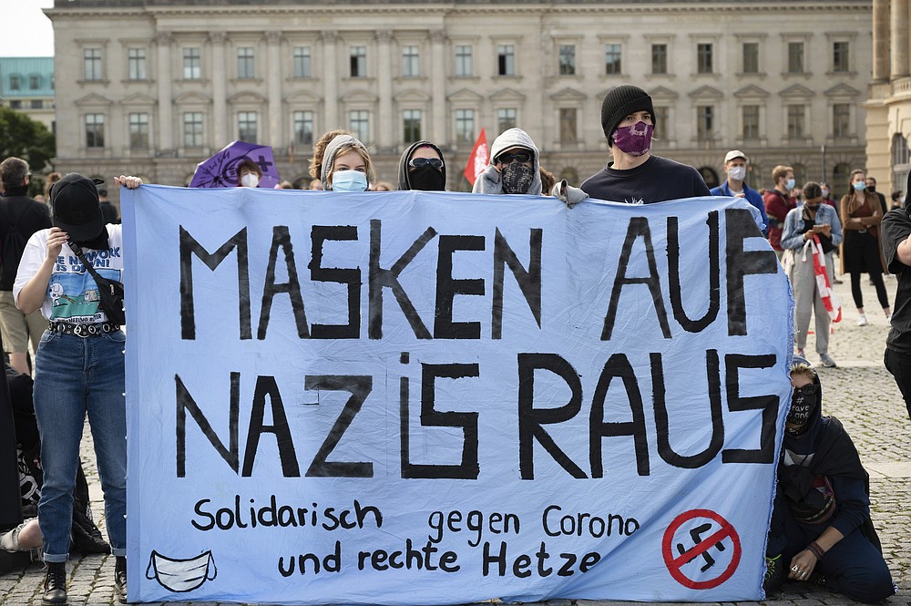 Counter-demonstrators of a rally against the Corona measures gather and hold out a banner reading "Masks on Nazis out" in Berlin, Germany, Saturday, Aug. 29, 2020. (Christophe Gateau/dpa via AP)