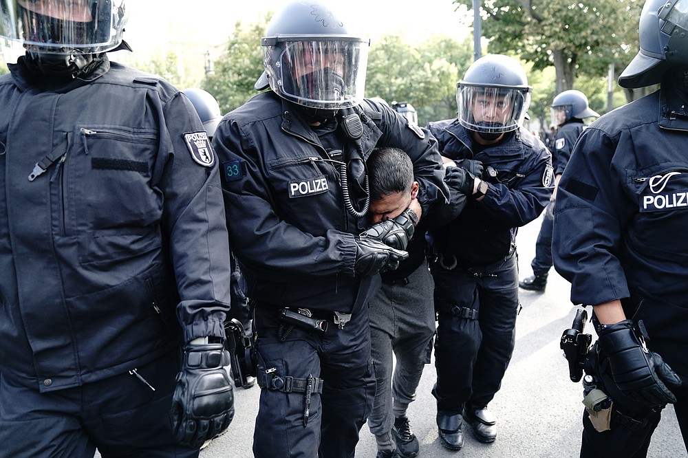 The police take vegan chef Attila Hildmann into custody during a demonstration against COVID-19 measures, in Berlin, Germany, Saturday, Aug. 29, 2020. Berlin police ordered a protest by people opposed to Germany’s pandemic restrictions to disband after participants refused to observe social distancing rules. Tens of thousands of people had gathered at the  Brandenburg Gate before marching through the German capital in a show of defiance Saturday against Germany's coronavirus prevention measures.   (Kay Nietfeld/dpa via AP)