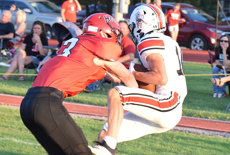 RICK PECK/SPECIAL TO MCDONALD COUNTY PRESS McDonald County wide receiver Jack Parnell holds on to a touchdown pass from Cole Martin after being hit by Aurora's Kohl Rohlman in the end zone during the Mustangs' 50-36 loss on Aug. 28 in Aurora.