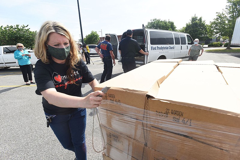 GIVEAWAY HELPS BY THE GALLON
Rachel Cox, executive director of Compassion House, opens Tuesday June 23 2020 a bundle of boxes filled with gallons of milk during the Mayor's Milk Initiative free milk distribution at Bentonville Fire Station No. 1 near downtown Bentonville. Some 4,800 gallons of milk donated by the Borden dairy company were given away to 35 food pantries and other area nonprofit groups, said Debbie Griffin, community relations and economic development director with the city of Bentonville. Families were eligible to receive milk once the needs of the nonprofit groups were filled. Whole milk and 2% milk was given away. Go to nwaonline.com/200624Daily/ to see more photos.
(NWA Democrat-Gazette/Flip Putthoff)