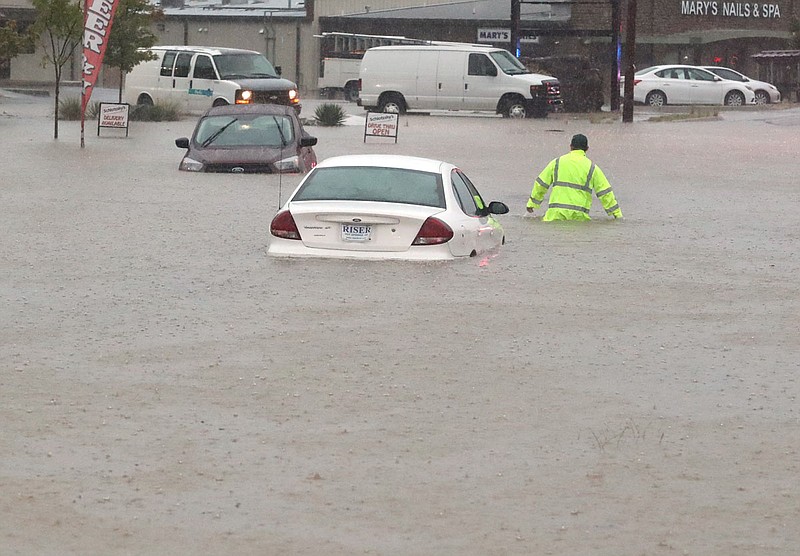 Hot Springs Parks and Trails Department employee Lucas Mason wades through high water on Central Avenue Monday, Aug. 31, near the intersection with Franklin Street. - Photo by Richard Rasmussen of The Sentinel-Record