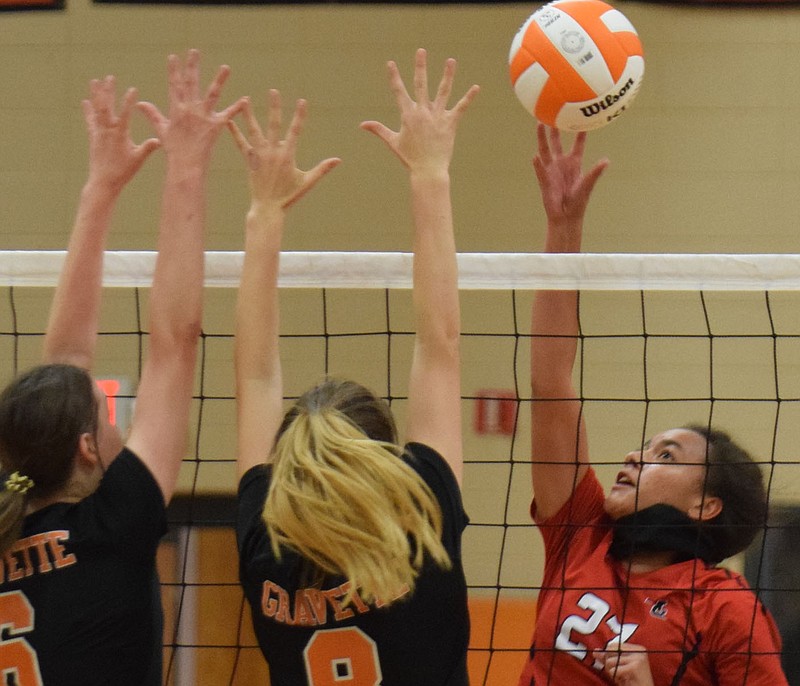 RICK PECK/SPECIAL TO MCDONALD COUNTY PRESS McDonald County's Shye Hardin tips the ball over a pair of Gravette defenders during the Lady Mustangs' 23-25, 25-10, 25-20, 25-15 win on Aug. 31 at Gravette High School.