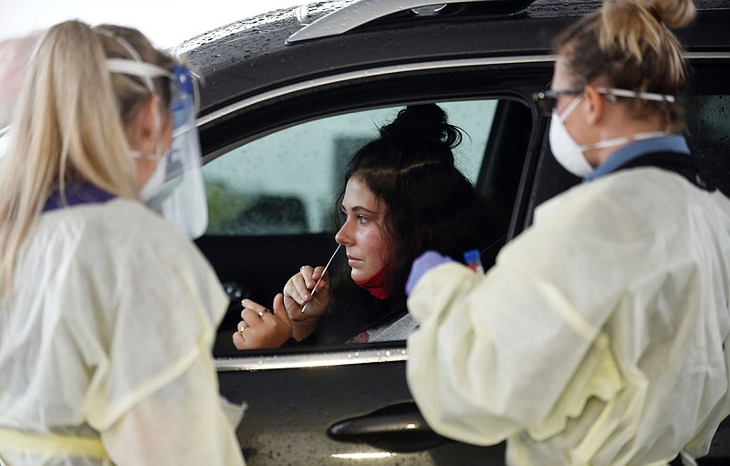 Karson Freeman, a freshman at the University of Arkansas from Little Rock, inserts a long swab Tuesday, September 1, 2020, into her nasal cavity during a drive-thru covid-19 testing clinic set up across from Baum-Walker Stadium at the corner of South Razorback Road and West 15th Street in Fayetteville. (NWA Democrat-Gazette/David Gottschalk)