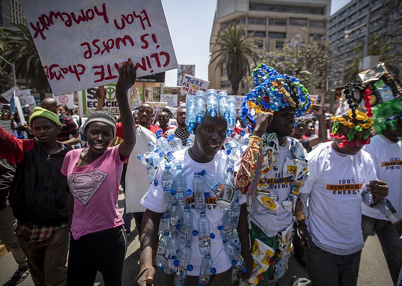 FILE - In this Friday, Sept. 20, 2019 file photo, around a thousand protesters, some wearing outfits made from plastic bottles and bottle-tops to raise the issue of plastic pollution, march to demand action on climate change, in the streets of downtown Nairobi, Kenya. The oil industry in 2020 has asked the United States to pressure Kenya to change its world-leading stance against the plastic waste that litters Africa, according to environmentalists who fear the continent will be used as a dumping ground. (AP Photo/Ben Curtis, File)