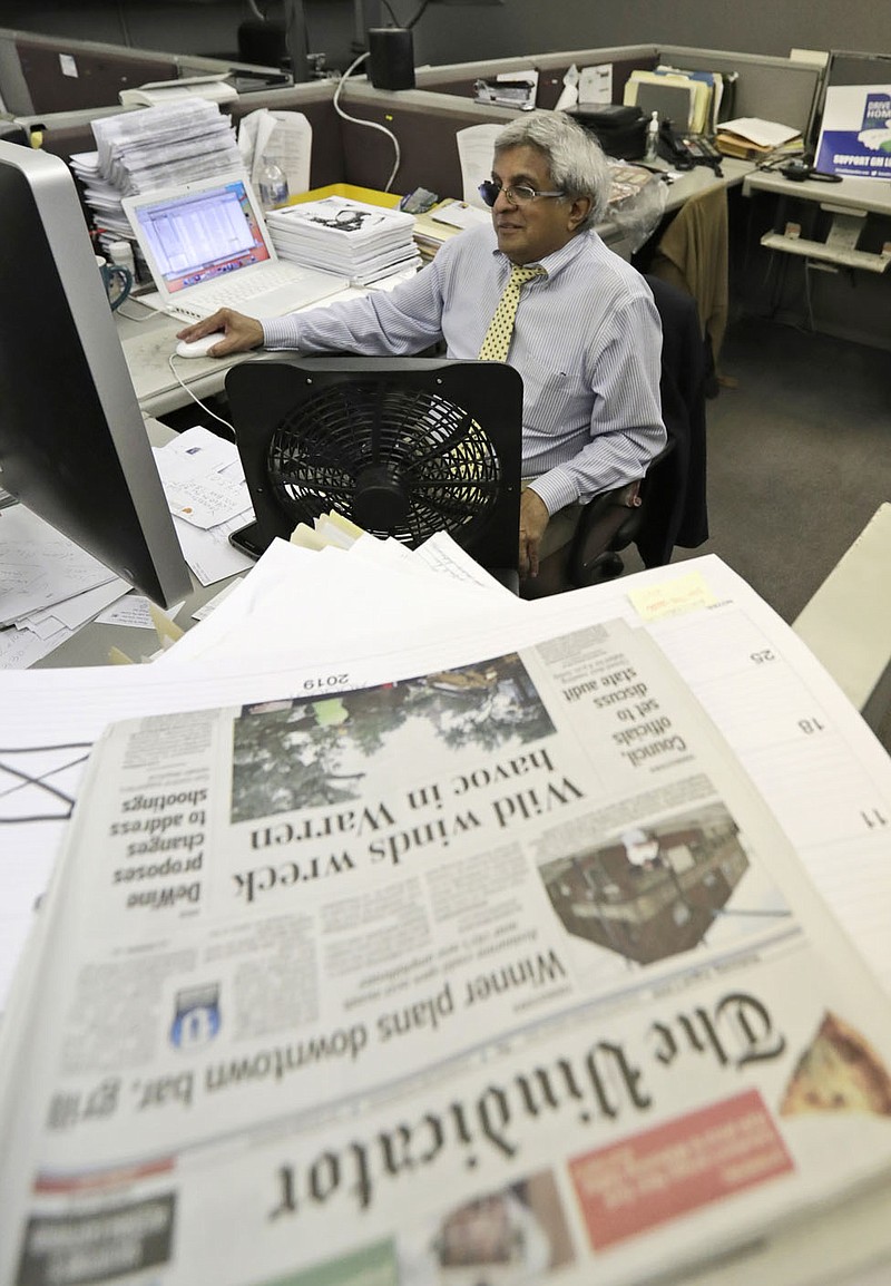 FILE - In this Aug. 7, 2019, file photo, Bertram de Souza works on a story for The Vindicator newspaper in Youngstown, Ohio. The Vindicator, a 150-year-old paper that shut down last year because of financial struggles, is being celebrated in a new book on the anniversary of its final edition. "No Holds Barred" collects hundreds of columns by de Souza, the paper's long-time political columnist. It also features multiple historic photos and reminiscences by former writers and editors at the paper, whose closing, one of the biggest U.S. papers to disappear to date, left a hole in northeastern Ohio media coverage. (AP Photo/Tony Dejak, File) story.lead_photo.caption