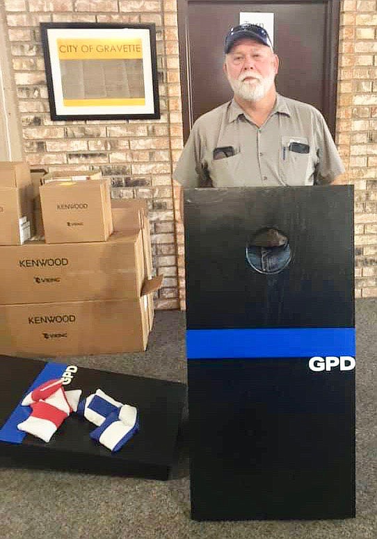 Submitted Photo
Tim DeWitt, Gravette's street and parks department supervisor, displays the set of custom cornhole boards he made. The set, which includes two boards and the weighted throwing bags shown on the floor, is being raffled off to benefit the Gravette Police Department's annual Shop with a Cop program.