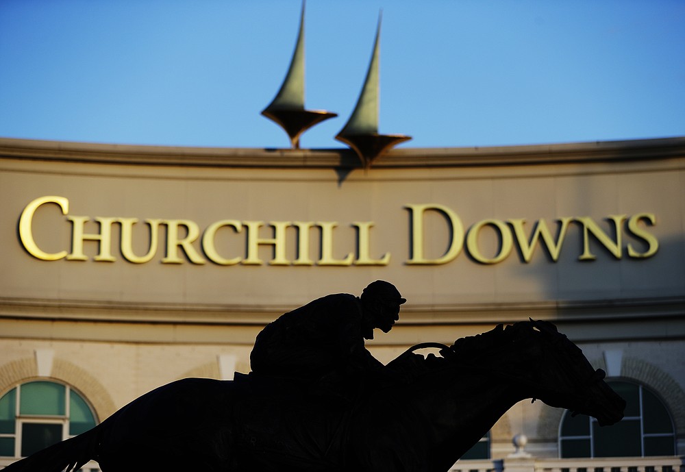 FILE - In this May 6, 2020 file photo a statue of Barbaro is silhouetted at the entrance of Churchill Downs in Louisville, Ky. The fastest two minutes in sports will also be the quietest in Kentucky Derby history. Churchill Downs scraped plans earlier this month for 23,000 physically distanced, masked fans to attend Saturday's rescheduled Tripled Crown race due to the rise in coronavirus cases. It will be the first time spectators will not be allowed to attend the race (AP Photo/Darron Cummings, File)