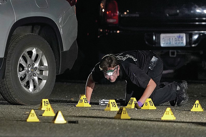 A Washington State Patrol Crime Lab worker looks at evidence markers in the early morning Friday in Lacey, Wash., at the scene where Michael Reinoehl was killed Thursday night as investigators moved in to arrest him.
(AP/Ted S. Warren)