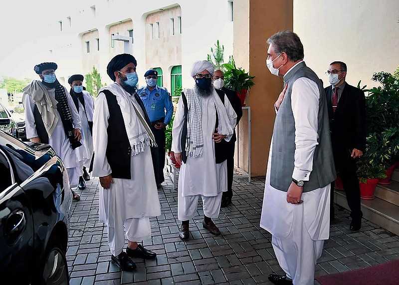 In this photo provided by Pakistan's Ministry of Foreign Affairs, Foreign Minister Shah Mahmood Qureshi, right, greets members of a Taliban political team on their arrival at the Foreign Ministry for talks, in Islamabad, Pakistan, Tuesday, Aug. 25, 2020. The team arrived in Pakistan on Monday as efforts appear to be ramping up to get negotiations underway between the Afghan government and the insurgents. The start of the talks, envisaged under a U.S.-Taliban peace agreement signed in February, was hampered by a series of delays that have frustrated Washington. (Pakistan Ministry of Foreign Affairs via AP)