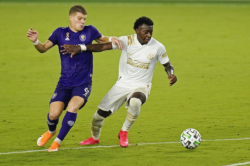 Orlando City's Chris Mueller (9) and Atlanta United's George Bello, right, fight for possession of the ball during the second half of Saturday's MLS match in Orlando, Fla. - Photo by John Raoux of The Associated Press