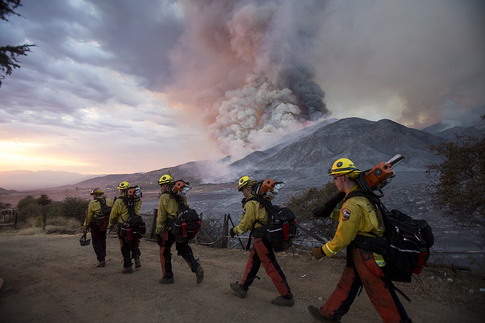 Members of firefighters walk in line during a wildfire in Yucaipa, Calif., Saturday, Sept. 5, 2020. Three fast-spreading California wildfires sent people fleeing Saturday, with one trapping campers at a reservoir in the Sierra National Forest, as a brutal heat wave pushed temperatures into triple digits in many parts of state.(AP Photo/Ringo H.W. Chiu)