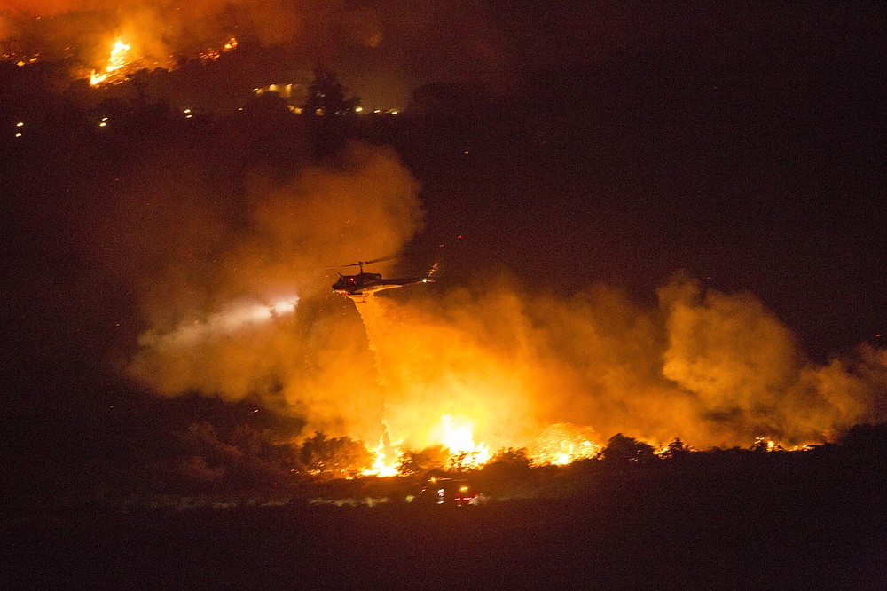 A helicopter drops water at a wildfire in Yucaipa, Calif., Saturday, Sept. 5, 2020. Three fast-spreading California wildfires sent people fleeing Saturday, with one trapping campers at a reservoir in the Sierra National Forest, as a brutal heat wave pushed temperatures into triple digits in many parts of state.(AP Photo/Ringo H.W. Chiu)