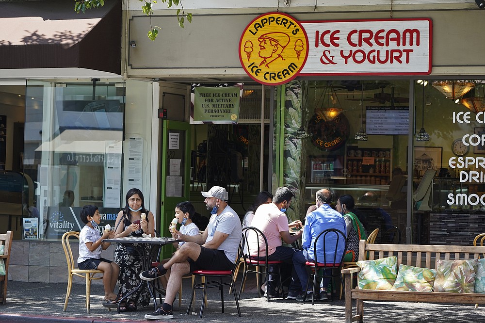 People eat ice cream outside a shop Saturday, Sept. 5, 2020, in Sausalito, Calif. California is sweltering under a dangerous Labor Day weekend heat wave that was expected to spread triple-digit temperatures over much of the state while throngs of people might spread the coronavirus by packing beaches and mountains for relief. (AP Photo/Eric Risberg)