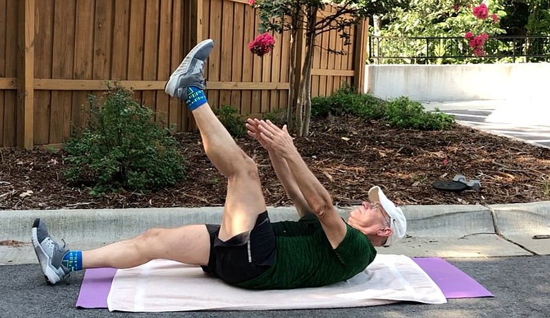 Eddie Dunn demonstrates step 4 of the Pulsing V Up for Matt Parrott's Master Class in the lower parking lot at Little Rock Racquet Club. (Democrat-Gazette/Celia Storey)