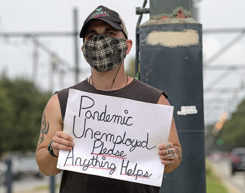 Sean Harris holds a sign asking for help while standing on the neutral ground on Carrollton Ave. at Bienville Ave. in New Orleans, Friday, Sept. 4, 2020. Harris had just completed training to be a hunted history tour guide in the French Quarter when the coronavirus pandemic hit. He has not been able to find a job since. (Max Becherer/The Times-Picayune/The New Orleans Advocate via AP)