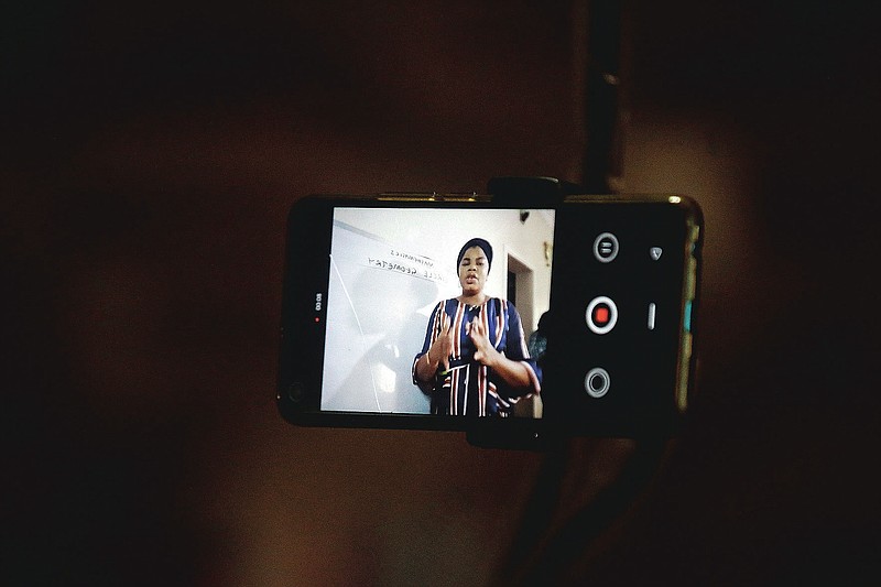 Mathematics teacher Basirat Olamide Ajayi, 36, teaches online via her mobile phone from her house in Lagos, Nigeria Saturday, Aug. 15, 2020. The teacher from a Lagos public school is helping students across the country, and internationally, learn math virtually during coronavirus restrictions that have prevented most children from returning to class in Nigeria. (AP Photo/Sunday Alamba)