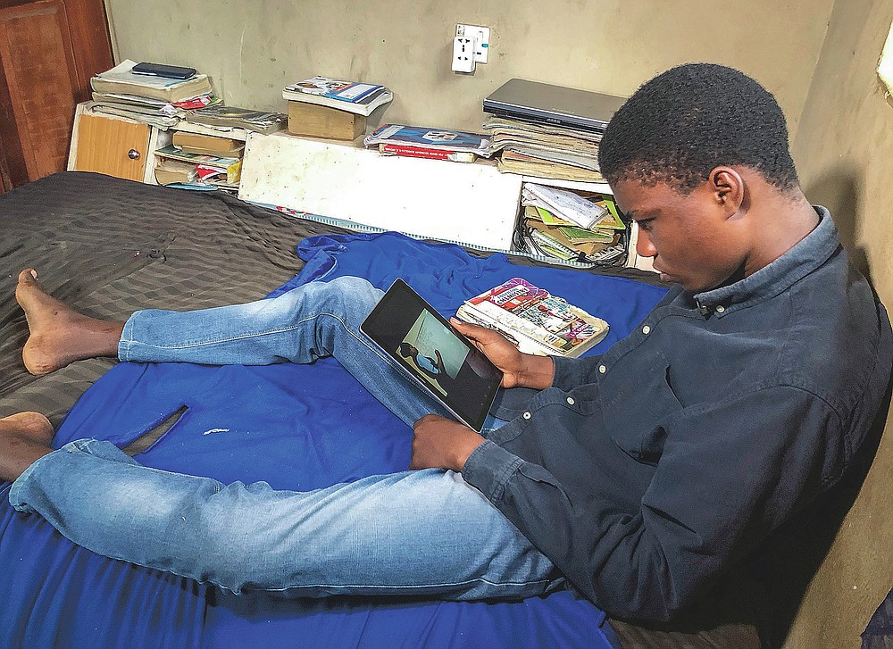 Student Fortune Declan watches an online class in mathematics taught by Basirat Olamide Ajayi, inside his house in Lagos, Nigeria Tuesday, Aug. 25, 2020. The teacher from a Lagos public school is helping students across the country, and internationally, learn math virtually during coronavirus restrictions that have prevented most children from returning to class in Nigeria. (AP Photo/Lekan Oyekanmi)