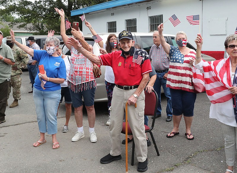 World War II veteran Ralph King, with cane, waves as a parade in his honor passes by VFW Post 2278 on East Grand Avenue on Friday. In honor of Patriot Day, Home Based Primary Care conducted individual parades for World War II veterans, including three in Hot Springs. - Photo by Richard Rasmussen